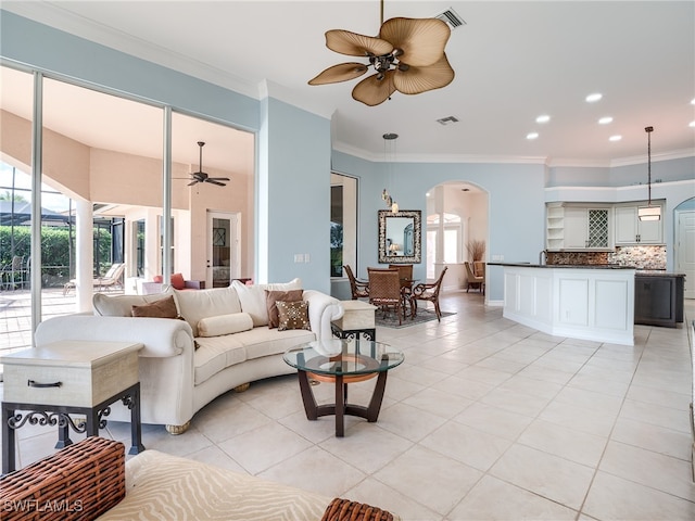 tiled living room with ceiling fan and crown molding