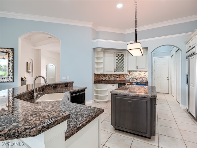 kitchen featuring pendant lighting, dishwasher, sink, an island with sink, and ornamental molding