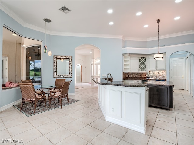 kitchen with pendant lighting, tasteful backsplash, a kitchen island, light tile patterned floors, and crown molding