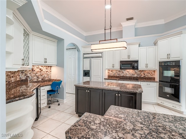 kitchen with dark stone countertops, a kitchen island, built in desk, and black appliances