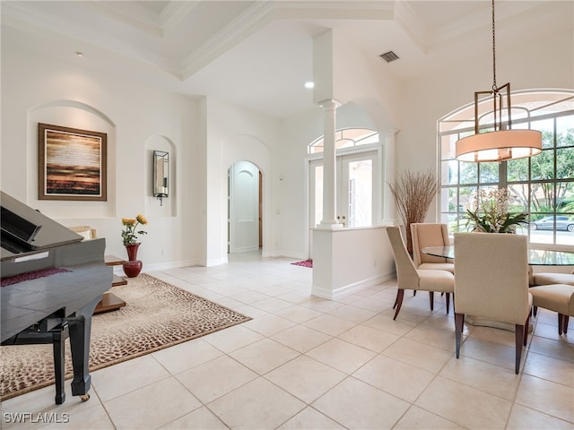 tiled dining space featuring ornamental molding, a wealth of natural light, a towering ceiling, and decorative columns