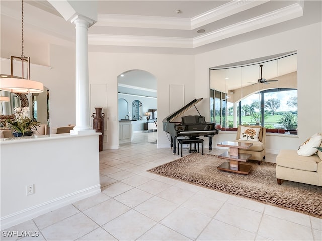 tiled living room with ornate columns, ceiling fan, a raised ceiling, and crown molding