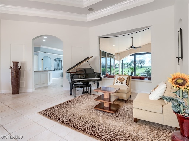 living area with ceiling fan, tile patterned floors, and crown molding