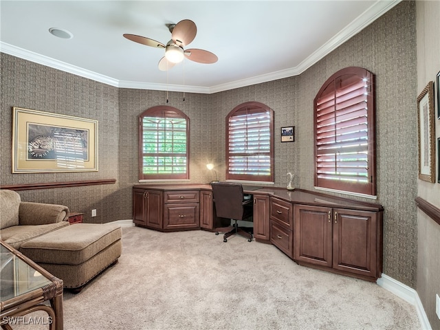 office area with built in desk, crown molding, ceiling fan, and light colored carpet