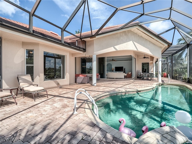 view of swimming pool featuring glass enclosure, ceiling fan, a patio area, and an outdoor hangout area