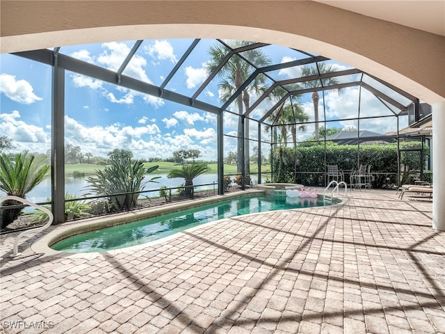 view of swimming pool featuring glass enclosure, a water view, a patio area, and an in ground hot tub