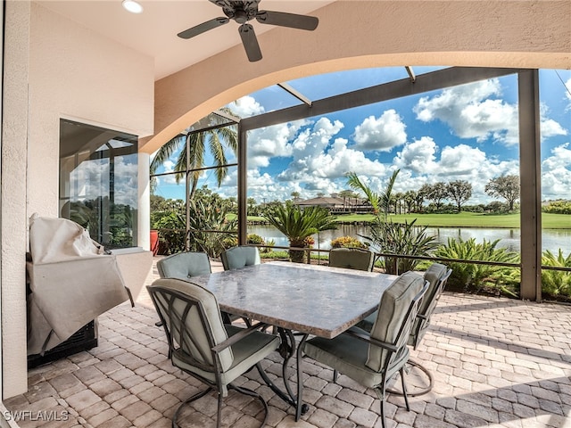 view of patio / terrace with a lanai, a water view, and ceiling fan