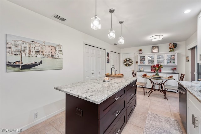 kitchen featuring light tile patterned flooring, stainless steel dishwasher, dark brown cabinets, decorative light fixtures, and white cabinetry