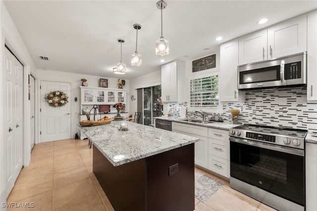 kitchen with white cabinets, stainless steel appliances, sink, and a center island