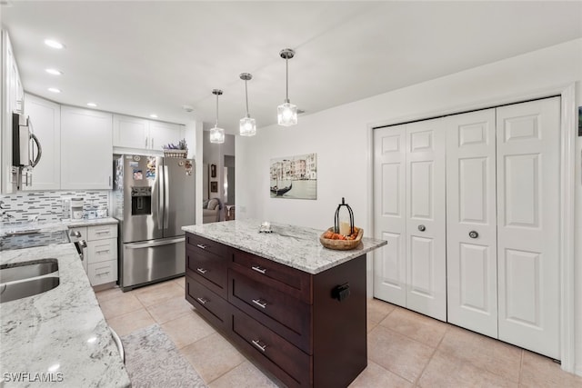 kitchen with pendant lighting, a center island, white cabinets, stainless steel appliances, and light stone countertops