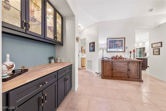 bar featuring butcher block counters and light tile patterned floors