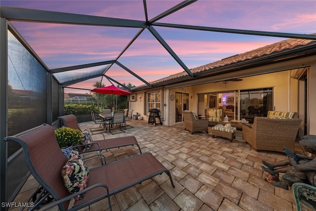 patio terrace at dusk with a lanai and an outdoor living space