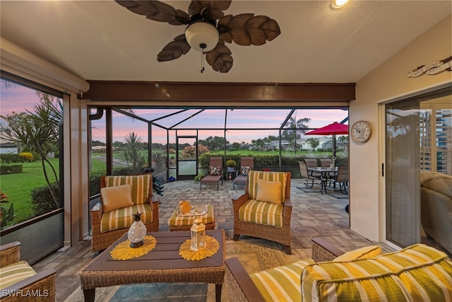 patio terrace at dusk featuring ceiling fan, an outdoor living space, and a lanai