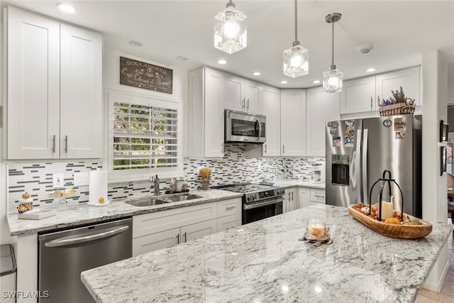 kitchen featuring appliances with stainless steel finishes, hanging light fixtures, and white cabinetry