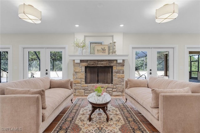 living area with a stone fireplace, french doors, wood finished floors, and recessed lighting