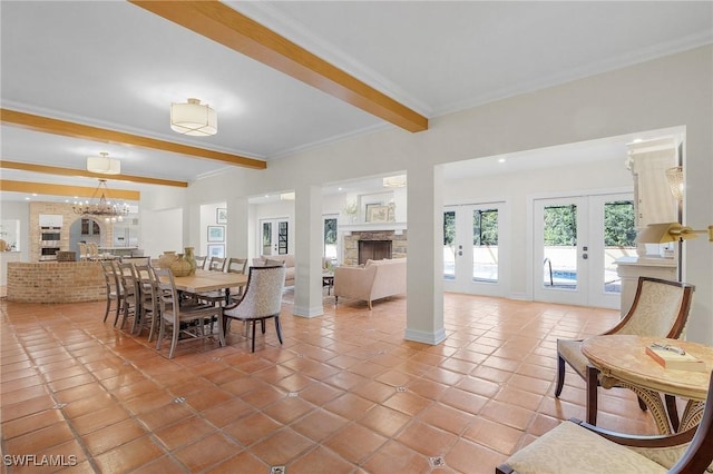 tiled dining space with beam ceiling, french doors, an inviting chandelier, a fireplace, and ornamental molding