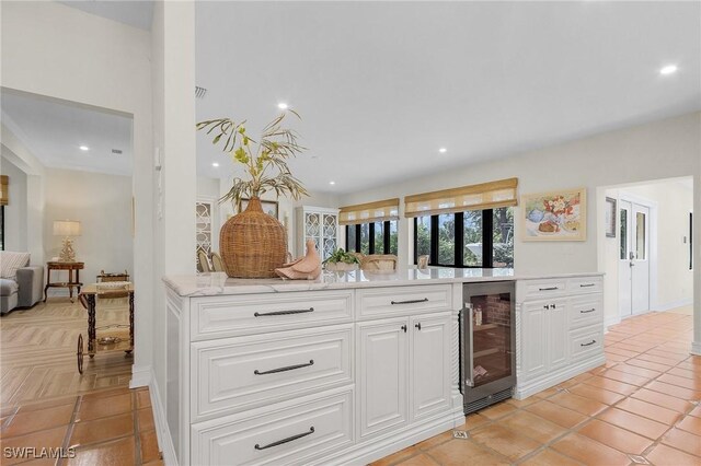 kitchen featuring white cabinets, light tile patterned floors, light stone countertops, and beverage cooler