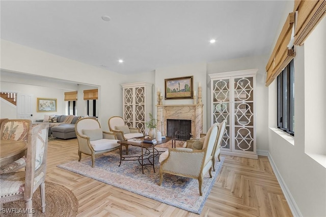 living room featuring a high end fireplace and light parquet flooring