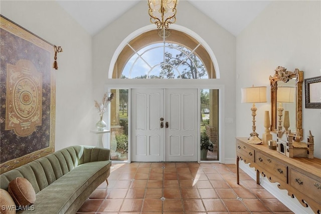 foyer entrance with high vaulted ceiling, a chandelier, and tile patterned floors