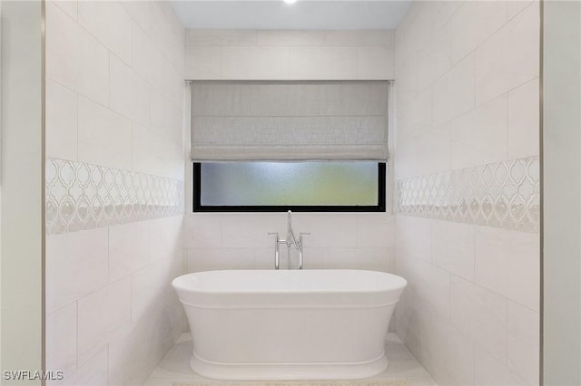 bathroom with a bathtub and tile walls