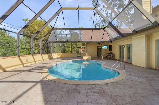 outdoor pool with ceiling fan, glass enclosure, and a patio area