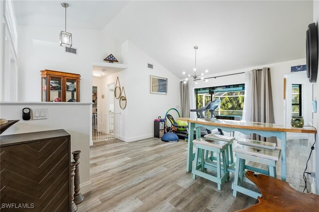 dining room featuring a notable chandelier, light wood-type flooring, and high vaulted ceiling