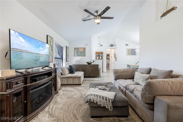 living room featuring ceiling fan, light wood-type flooring, and vaulted ceiling