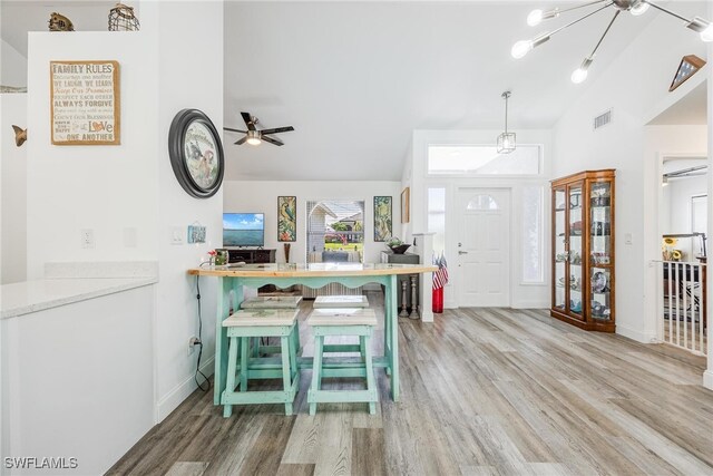 kitchen featuring kitchen peninsula, hardwood / wood-style floors, a breakfast bar, and vaulted ceiling