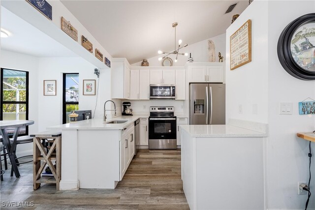 kitchen featuring white cabinets, kitchen peninsula, hanging light fixtures, and appliances with stainless steel finishes