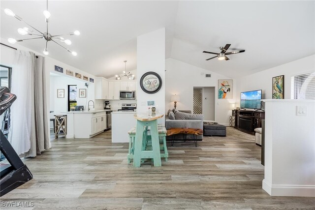 interior space featuring kitchen peninsula, stainless steel appliances, white cabinetry, and lofted ceiling