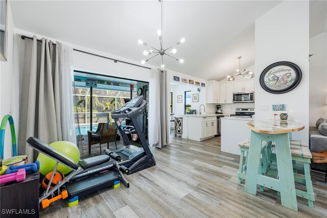 exercise area with a chandelier, sink, high vaulted ceiling, and light hardwood / wood-style flooring