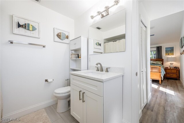 bathroom with wood-type flooring, vanity, and toilet