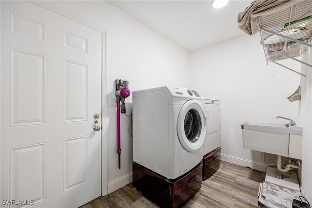 clothes washing area featuring independent washer and dryer, sink, and hardwood / wood-style floors