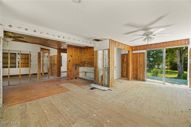 interior space featuring light hardwood / wood-style floors, wooden walls, and ceiling fan