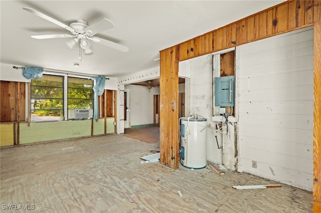 spare room with electric water heater, cooling unit, ceiling fan, wooden walls, and electric panel