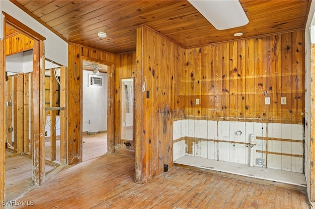 spare room with light wood-type flooring, wooden walls, and wooden ceiling