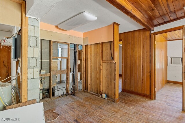 misc room with wooden walls, light hardwood / wood-style floors, and beamed ceiling