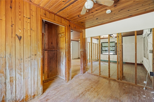 hallway with wooden walls, light hardwood / wood-style floors, and wooden ceiling