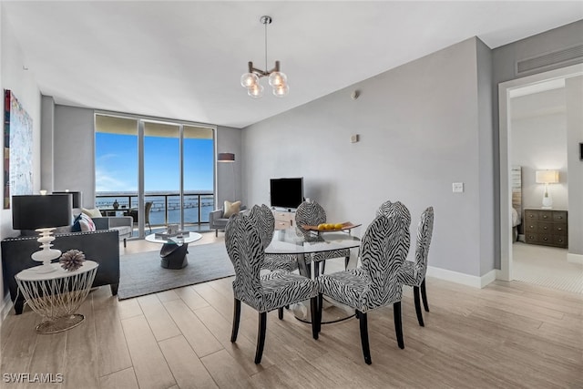 dining space with a notable chandelier, a wall of windows, and light hardwood / wood-style floors