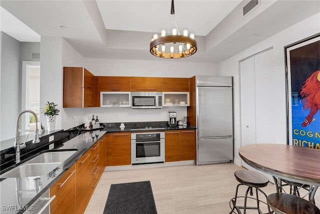 kitchen featuring an inviting chandelier, sink, light wood-type flooring, and appliances with stainless steel finishes