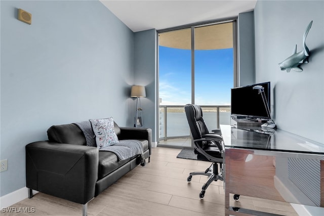 home office featuring floor to ceiling windows and light wood-type flooring