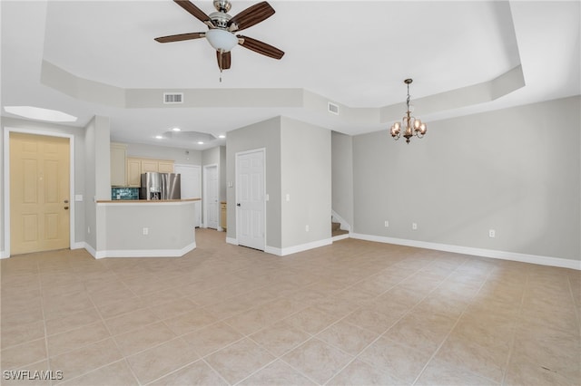 unfurnished living room with ceiling fan with notable chandelier, a raised ceiling, and light tile patterned flooring