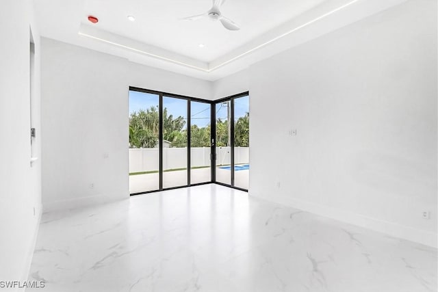 empty room featuring a raised ceiling and ceiling fan