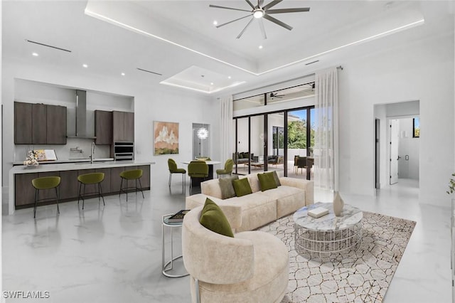 living room featuring a towering ceiling, a raised ceiling, and sink