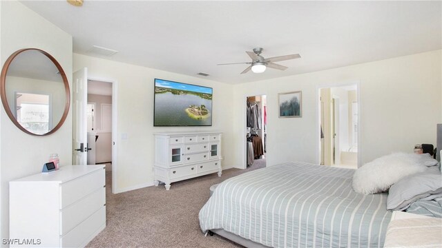 carpeted bedroom featuring ceiling fan, a closet, a spacious closet, and ensuite bath