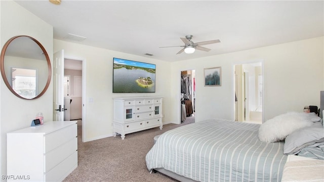 bedroom with a walk in closet, a closet, visible vents, light carpet, and ensuite bath