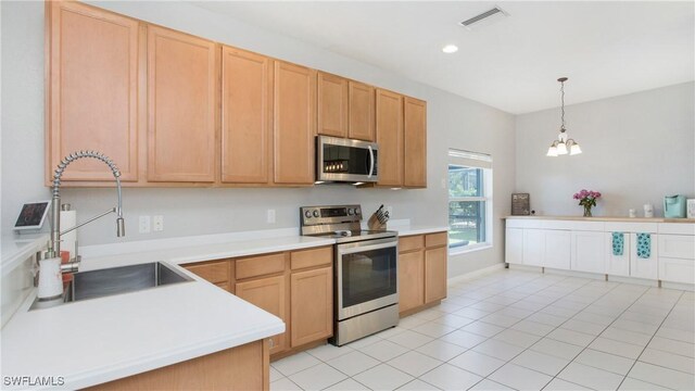 kitchen featuring pendant lighting, light brown cabinets, appliances with stainless steel finishes, a notable chandelier, and light tile patterned flooring