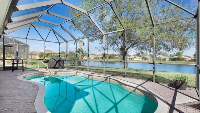 view of pool with a patio area, a water view, and glass enclosure