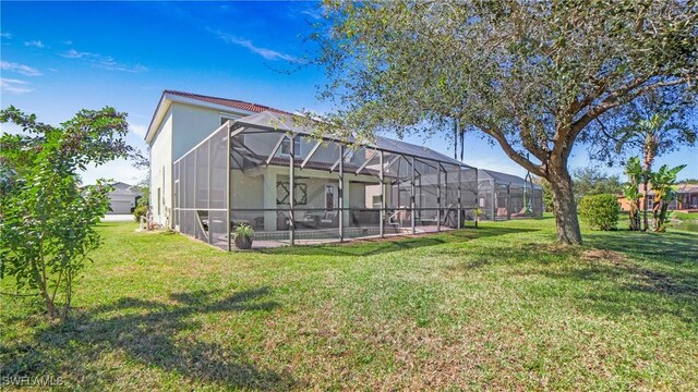 back of property featuring glass enclosure and a lawn