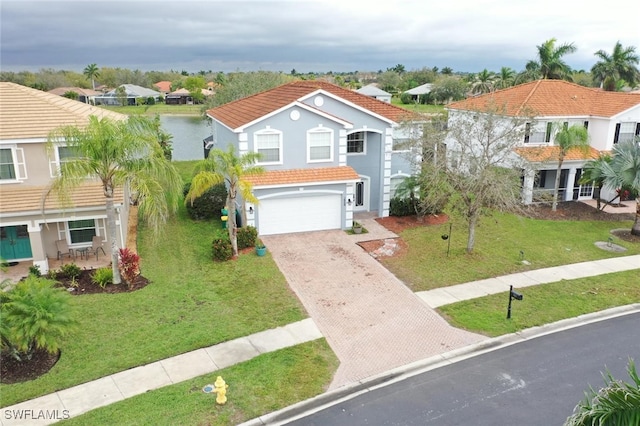 mediterranean / spanish-style house with an attached garage, a water view, a tile roof, decorative driveway, and a residential view